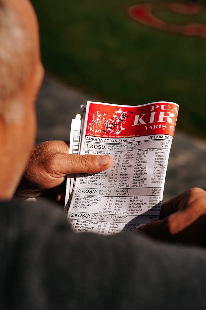 Adult man reading a racing newspaper on a sunny day in Ankara, Türkiye. Close-up shot.