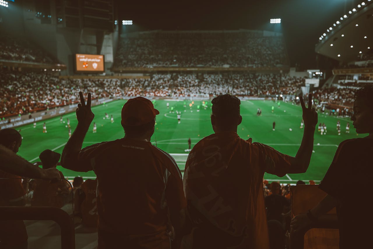 A vibrant football match with fans cheering in an illuminated stadium.